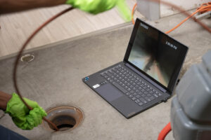 Professional sewer camera inspection detecting blockages in a residential drain system, displayed on a laptop screen.