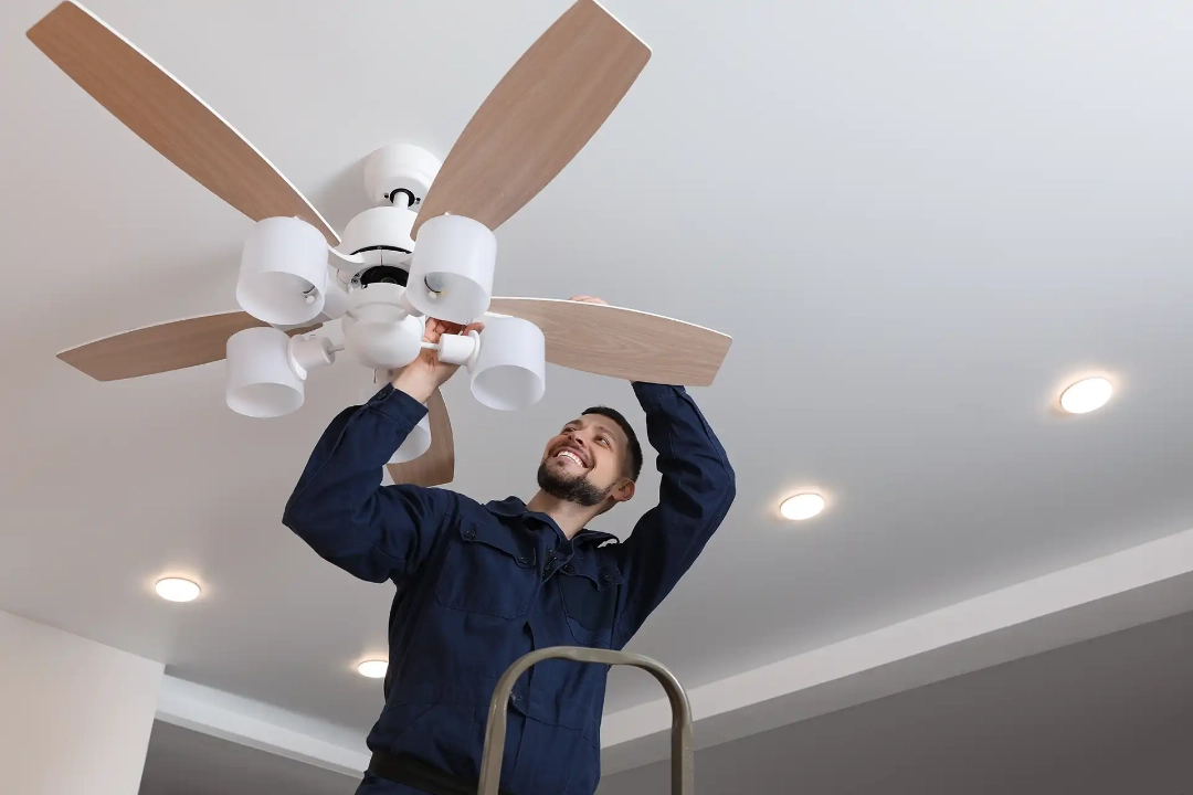 An electrician installing a ceiling fan